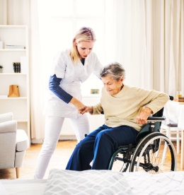 caregiver assisting senior woman to stand up in the wheelchair