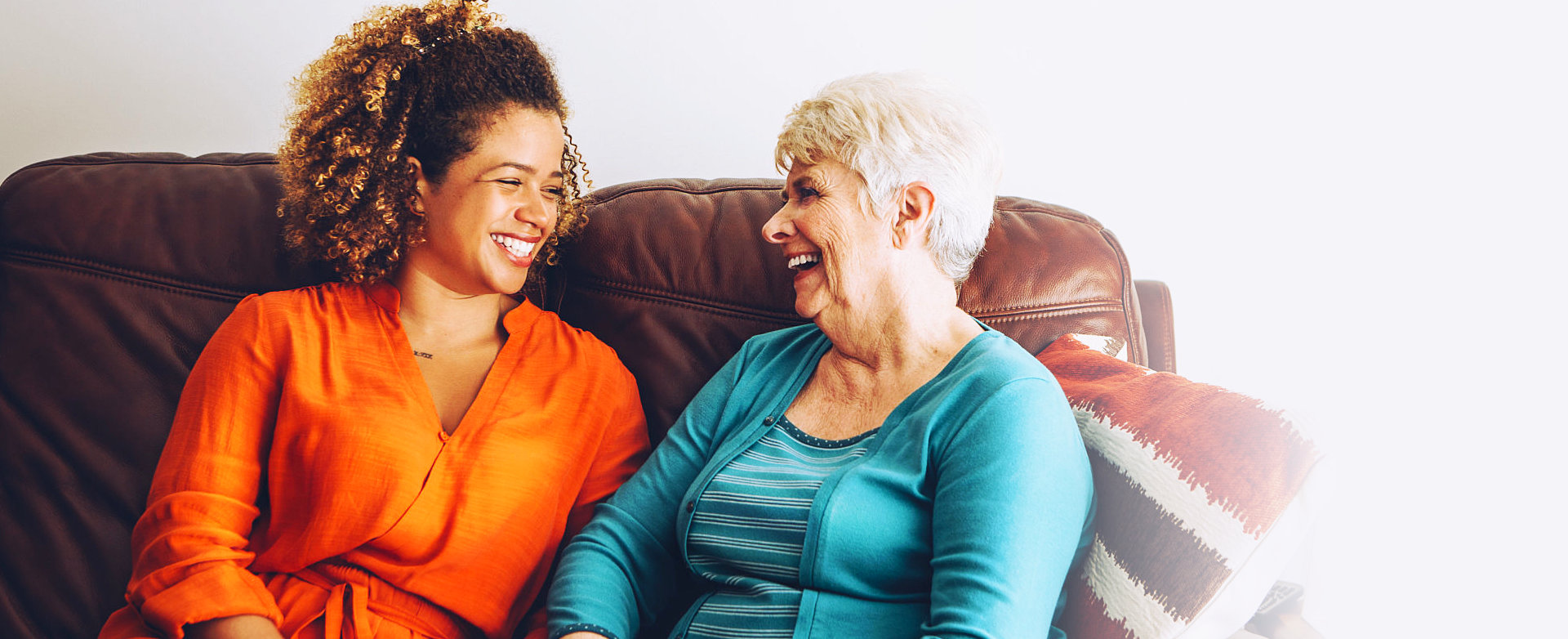 adult woman and senior woman sitting on the sofa smiling