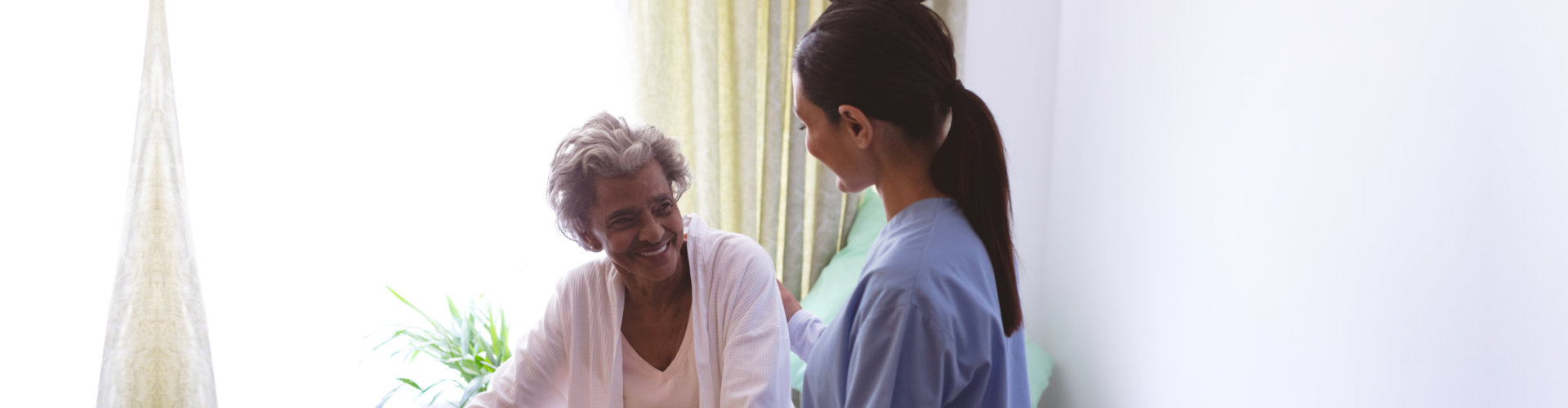caregiver looking at a senior woman smiling