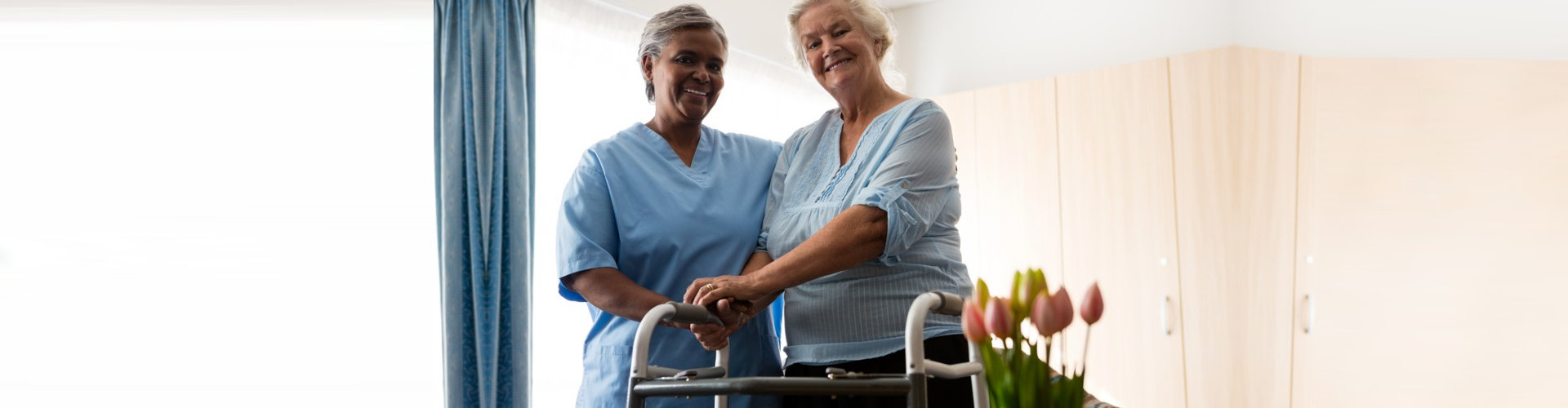 caregiver and senior woman holding her walking frame smiling